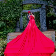 A romantic pose on a grand staircase, with the vibrant red gown flowing down the steps. This is a classic cinematic shot that feels both elegant and passionate.