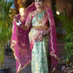 A full-length portrait of a stunning South Indian bride. This shot showcases her beautiful mint and pink Kanjivaram saree and the intricate gold jewelry, including the traditional waist belt (oddiyanam).