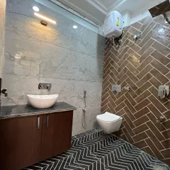 We used bold, contrasting patterns in this bathroom to create a dynamic and modern look. The shower wall features a dark brown herringbone tile, while the floor has a striking black-and-white chevron pattern.