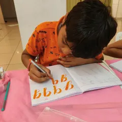 Intense concentration from this young boy as he practices his 'b's. Practice is essential for mastering the flow of brush calligraphy.