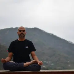 A student practices meditation against the backdrop of the mountains. This posture, Padmasana or the lotus pose, is an ideal asana for prolonged periods of meditation and pranayama.