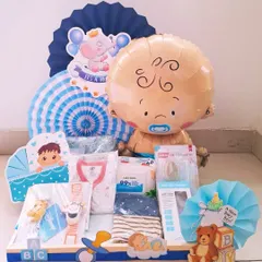 This welcome hamper for a baby boy features a large baby-faced balloon and an adorable elephant motif. It's filled with practical items like baby wipes, clothes, and a pacifier.