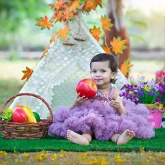This little one is enjoying a healthy snack in our colorful tent setup. These themed shoots are perfect for capturing your child's personality in a fun and imaginative setting.