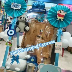 This is a Shinchan themed first birthday hamper for a baby boy named Maanveer. It includes clothes, soft toys, and other goodies in a coordinated blue theme.