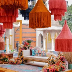 The bride's seating for the Soukh Bazaar Mehendi, framed by a cascade of colorful, oversized tassels and vibrant floral arrangements. This setup is a modern, elevated take on traditional Mehendi decor.