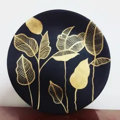 A modern take on botanical art, created with shimmering gold leaf on a dark circular canvas. I love how the simple, elegant leaf designs catch the light, making it a unique piece of home decor.