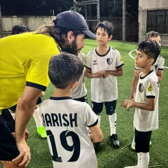A coach engages with our young players during a team talk. We believe in asking questions and mentoring to develop not just skilled athletes, but thoughtful individuals.