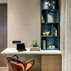 A chic and modern workspace featuring a floating white desk and a striking blue asymmetrical bookshelf. Integrated downlights in the shelves provide excellent task lighting.