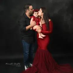 An intimate family moment. The parents tenderly kiss their daughter's cheeks, a beautiful gesture of love that stands out against the simple, dark background.