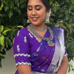 A smiling portrait of Dr. Indhu, showcasing her beautiful silver jhumkas and layered necklaces. This look is perfect for the bride who wants to stand out with a non-traditional choice.