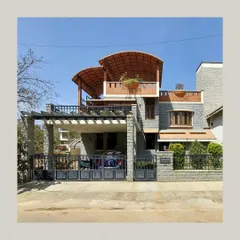 A residence featuring dramatic curved roofs and a mix of stone and brick textures, with a pergola over the driveway adding another layer of detail.