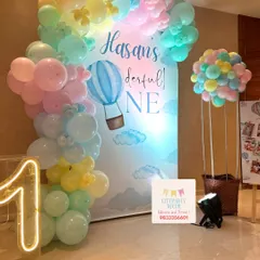A full view of the 'Onederful' hot air balloon party setup, showing the pastel balloon arch against the custom backdrop, the neon number '1', and the photo collage board on an easel.