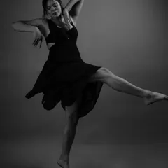 This dynamic pose captures a moment of powerful expression. In black and white, the focus shifts to the model's form, the flow of the dress, and the raw energy of the dance.