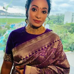 A portrait showcasing the soft glam makeup against her beautiful purple and gold saree. The look is elegant, radiant, and perfect for a South Indian wedding.