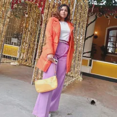 This full-length shot shows how the color-blocked outfit comes together. The bright coat and pants make a statement, while the neutral white shoes and simple bag keep the look balanced.