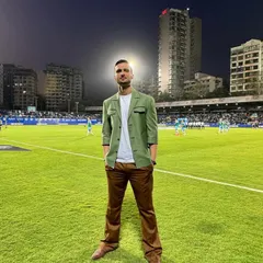 A standout look for Karan Sawhney at the ISL broadcast. The combination of a structured green jacket, a simple white tee, and brown trousers creates a fresh and modern on-air style.