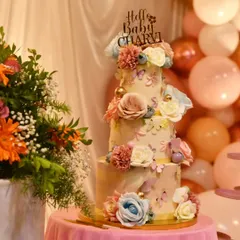 An elegant 8 kg, three-tier, no-fondant cake for a baby's meet and greet party. The design features delicate sugar flowers and butterflies, creating a whimsical and sophisticated centerpiece.
