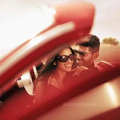 A candid, sun-drenched shot from inside the vintage car, capturing the couple's laughter. The warm lighting and tight framing create an intimate and joyful pre-wedding photograph.
