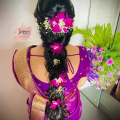 A close-up of a modern messy braid decorated with beautiful orchids. This hairstyle is a great choice for receptions, engagements, or any special party.