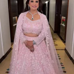 A full-length portrait of the groom's mother. She looks absolutely regal in her sequined pink lehenga, with makeup that enhances her grace.
