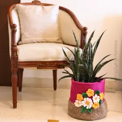 A quiet corner featuring one of my two-toned crochet baskets used as a beautiful planter cover. The bright pink top half is decorated with delicate white and yellow crochet flowers.