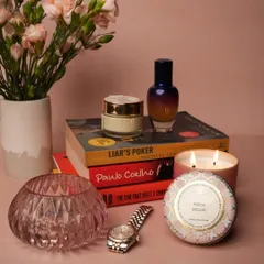 A moment of quiet luxury. Our Peach Bellini candle, made from a soft, creamy coconut wax blend, sits alongside other personal treasures. The beautiful tin and gentle light create a perfect ambiance for reading or relaxing.