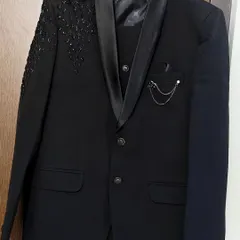 A classic black tuxedo-style suit with satin lapels and shoulder embellishments. This rental is a timeless choice for any formal event, from black-tie parties to elegant photoshoots.