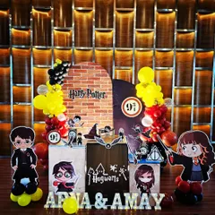 This Harry Potter setup for Arna and Amay's party is full of magical details. It includes a brick wall backdrop for Platform 9 3/4, cute chibi-style character cutouts, and pedestals themed after Hogwarts.
