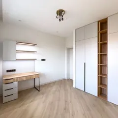 This room features a custom-built wardrobe and study unit. The combination of white and light wood finishes creates a modern and functional space, perfect for a bedroom or home office.