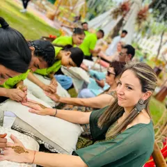 A happy guest getting her mehndi done at a beautiful outdoor event. My team ensures every guest receives a beautiful design and a wonderful experience.