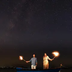 A bold and dramatic shot featuring a couple on a boat, holding flaming torches against the night sky. This is a perfect example of how we create high-impact, cinematic images for adventurous couples.