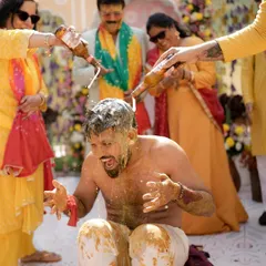 The groom is doused with beer and haldi by his friends and family, a moment of pure, uninhibited fun that showcases the lively spirit of the celebration.