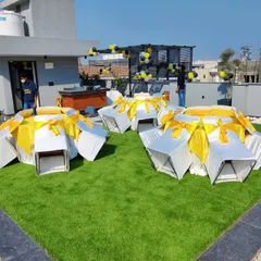 A birthday party setup on a residential rooftop with artificial grass. We arranged seating around circular tables, showing how we can adapt to smaller, unconventional spaces for private events.