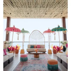 A vibrant and chic Haldi ceremony setup in Bali, featuring colorful Balinese umbrellas, custom macrame backdrops, and a stunning ocean view.