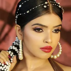 A portrait that showcases the entire headpiece and pearl-decorated braid, along with large hoop earrings. It’s a complete, high-fashion beauty look.