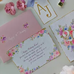 A flat lay of the complete birthday suite, including the hand-painted letter, a floral monogram card, a personalized tag, and a matching envelope.