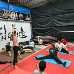 An instructor guiding the class through a wide-legged forward bend. Proper guidance is key to stretching safely and effectively.