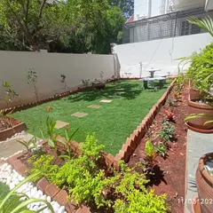 A view of a residential garden we designed, featuring a central lawn bordered by brick-edged flower beds. We selected a variety of plants to provide color and texture, and placed a stone fountain as a focal point.