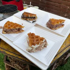 A platter of our freshly made waffles ready to be served. We offer a variety of toppings and sauces, allowing guests to customize their perfect dessert at your event.