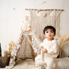 A thoughtful moment from a little one in a neutral, boho-chic setup. The teepee and macrame details create a calm and stylish atmosphere.