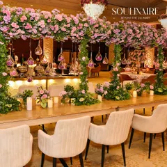 A stunning wedding dining setup featuring tables laden with lush pink floral arrangements and hanging glass ornaments. We craft immersive environments that blend romance and opulence.