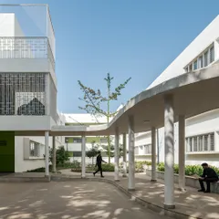 Circulation paths at Vidyashilp Academy are carefully designed to weave around mature trees, preserving the natural landscape. The curved, colonnaded walkway provides a shaded path that fosters a continuous connection with the outdoors, making the school feel like it breathes with its environment.