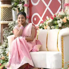 The complete look for Dr. Namratha's engagement. The light pink Kanchipuram saree is draped elegantly, and her hair is styled in a neat braid, suitable for the outdoor setting.