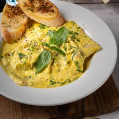 Comfort food, elevated. Our handmade ravioli is filled with delicate flavors and bathed in a velvety pumpkin sauce, served with garlic bread for a dish that feels both luxurious and heartwarming.