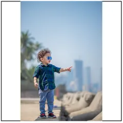 A stylish shot of a toddler enjoying the view at a Mumbai seaside location. The city skyline in the background provides a unique urban context for this child's portrait.