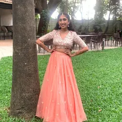 This client looks absolutely lovely in her custom crop top and skirt, perfect for a Sangeet. The embroidered blouse and flowing peach skirt create a look that is both festive and comfortable.