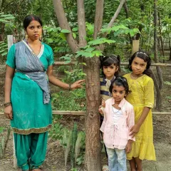 A mother and her children celebrate Vriksha Bandhan, tying a rakhi to a tree. By teaching children to see trees as protectors, we are fostering a generation that understands and respects its bond with nature.