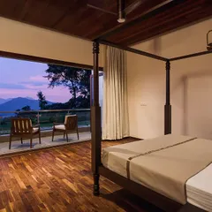 Simplicity and elegance define this bedroom, where a classic four-poster bed creates a sense of intimacy. The room opens onto a private balcony, offering a serene space to enjoy the twilight views over the mountains, blending comfort with the beauty of the outdoors.