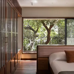 The design of this bedroom is all about framing the view. The window acts like a living painting, bringing the beauty of the mature trees directly into this private sanctuary.