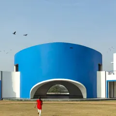 A child runs towards the bright blue amphitheater, a perfect image of how architecture can inspire joy and playfulness in learning environments.